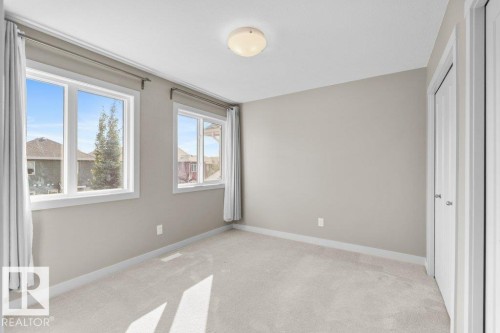 Light gray wall paint, two windows with white trim, flush mount ceiling light, and light-colored carpet flooring - 1523 168 Street Sw, Edmonton, AB 