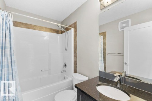 Bathroom featuring a shower-tub combination, a vanity with a dark countertop, and a built-in mirror - 1523 168 Street Sw, Edmonton, AB 