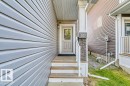 Front entry featuring a paneled door with glass insert, wood steps, and a white railing - 1523 168 Street Sw, Edmonton, AB 