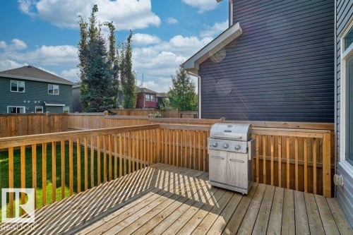 Spacious rear deck with wood railing, featuring a large backyard with a privacy fence and green lawn - 1523 168 Street Sw, Edmonton, AB 