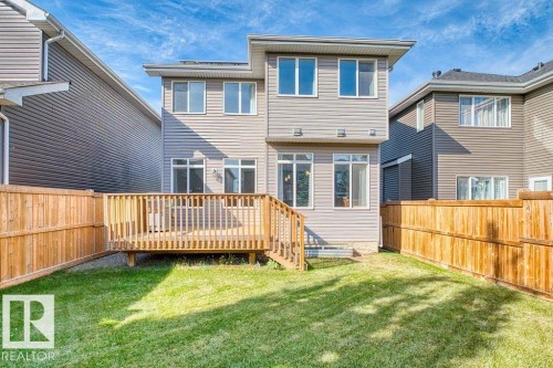Multi-story exterior with horizontal siding, featuring a wooden deck with railing, and a grass lawn enclosed by a wooden fence - 1523 168 Street Sw, Edmonton, AB 