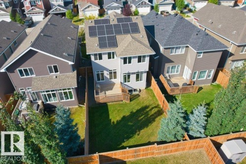 Rear exterior featuring a wood deck, fenced yard, solar panels, and multiple windows - 1523 168 Street Sw, Edmonton, AB 