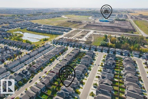 Expansive residential development with numerous single-family homes, a substantial commercial/institutional building, and a large natural pond surrounded by green space - 1523 168 Street Sw, Edmonton, AB 