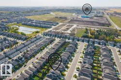 Expansive residential development with numerous single-family homes, a substantial commercial/institutional building, and a large natural pond surrounded by green space - 