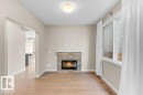 Stone-clad fireplace with an electric insert, wood-finish flooring, and a large window with white blinds - 1523 168 Street Sw, Edmonton, AB 