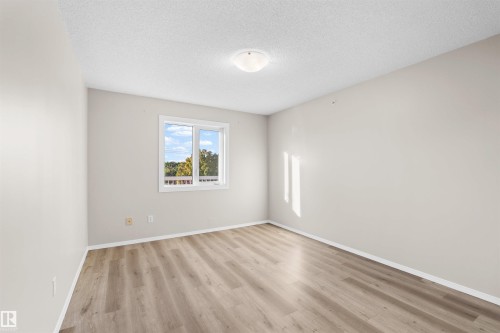Wood-finish flooring with neutral wall tones and a single window - #408 10610 76 St Nw, Edmonton, AB 