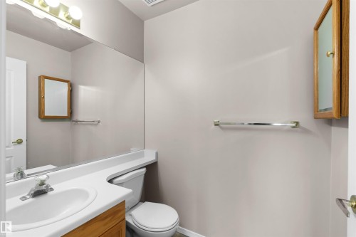 Bathroom featuring a vanity with an integrated sink, built-in mirror, wall-mounted medicine cabinet, toilet, and towel bar - #408 10610 76 St Nw, Edmonton, AB 