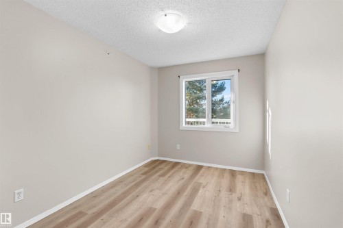 Wood-finish flooring, white trim, and a window with white framing - #408 10610 76 St Nw, Edmonton, AB 