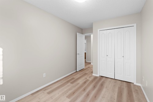Light neutral wall paint, wood-finish flooring, textured white ceiling, and a double bi-fold closet - #408 10610 76 St Nw, Edmonton, AB 