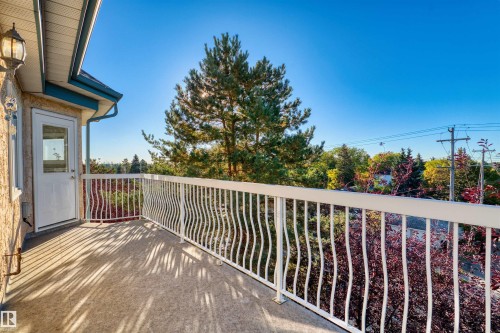 Outdoor balcony featuring a white decorative railing, textured exterior wall, and an exterior light fixture - #408 10610 76 St Nw, Edmonton, AB 