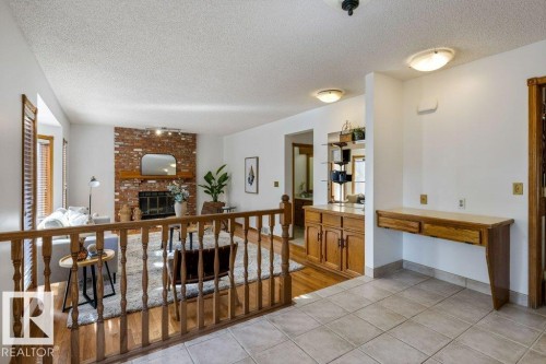 Exposed brick fireplace with a wood mantel, wood-finish flooring, built-in cabinetry, and tile flooring - 507 Burton Close Nw, Edmonton, AB 