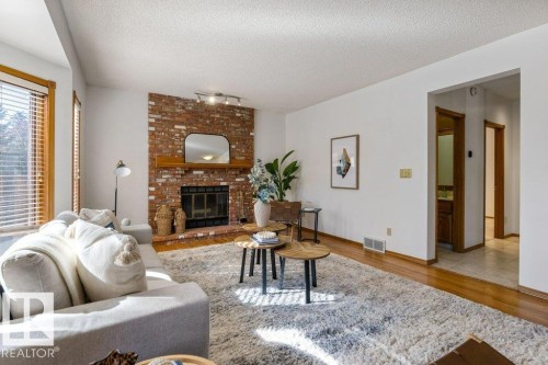 Brick fireplace with wood mantel, hardwood flooring, and neutral wall tones - 507 Burton Close Nw, Edmonton, AB 
