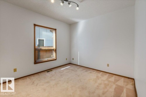 Corner room featuring a single window, track lighting, and carpeted flooring - 507 Burton Close Nw, Edmonton, AB 
