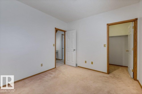 Spacious bedroom with neutral wall finishes, wood-finish framed doorways, and warm wood-finish flooring throughout - 507 Burton Close Nw, Edmonton, AB 