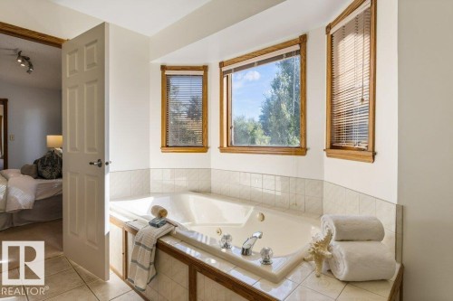 Built-in jetted tub with tile surround, wood-trimmed bay windows, and tile flooring - 507 Burton Close Nw, Edmonton, AB 