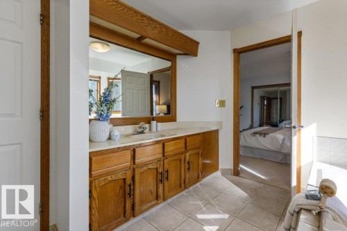 Wood-finish cabinetry with a light-toned countertop, integrated sink, and large wall mirror - 507 Burton Close Nw, Edmonton, AB 