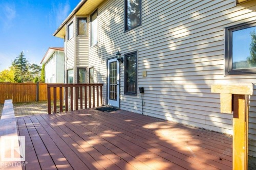 Expansive rear deck with wood railing, leading to a brick paver patio and full privacy fencing - 507 Burton Close Nw, Edmonton, AB 