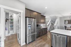 Wood-finish flooring, stainless steel appliances, dark wood cabinetry, white countertops, and a built-in pantry with shelving - 