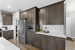 Modern kitchen featuring rich cabinetry, stainless steel appliances, white countertops, and a subway tile backsplash - 
