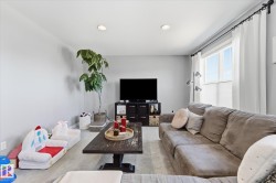 Recessed ceiling lighting, large window with privacy blinds, light wood-finish flooring, and light gray wall paint - 