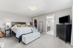 Carpeted bedroom featuring a flush-mount ceiling light, a built-in closet with shelving, and an adjacent bathroom with a vanity and toilet - 