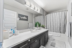 Double vanity with a white countertop and dark wood-finish cabinetry, a tiled backsplash, and a tub/shower combination - 