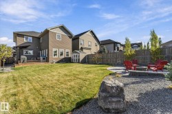 Expansive backyard featuring a manicured lawn, multi-level deck, gravel patio with a built-in fire pit, and a storage shed - 