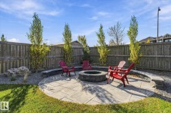 Backyard featuring a paver patio with a built-in stone fire pit, a curved stone retaining wall, and a wood fence - 