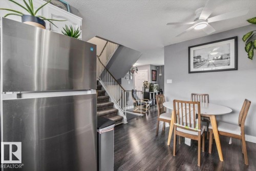 Wood-finish flooring, stainless steel refrigerator, white ceiling fan with integrated lighting, and a staircase with white railings - 1040 Lakewood Rd N Nw, Edmonton, AB 