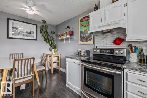 Updated kitchen with stainless steel range, subway tile backsplash, white upper cabinetry, and dark wood-finish flooring - 1040 Lakewood Rd N Nw, Edmonton, AB 
