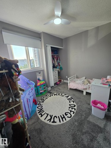 Recessed closet with built-in shelving, window with roller shade, ceiling fan with integrated lighting, and wall-to-wall carpeting - 1040 Lakewood Rd N Nw, Edmonton, AB 
