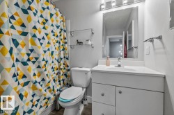 White vanity with an integrated sink and chrome faucet, under-sink cabinetry with polished chrome pulls, mirrored medicine cabinet with integrated lighting, and two glass shelving units - 