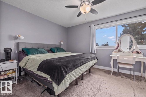 Soft gray wall paint, wall-mounted sconces, ceiling fan with integrated lighting, and a large window with white trim - 1040 Lakewood Rd N Nw, Edmonton, AB 