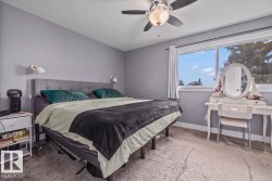 Soft gray wall paint, wall-mounted sconces, ceiling fan with integrated lighting, and a large window with white trim - 