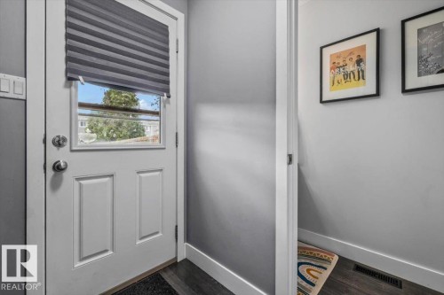 White paneled door with glass insert, dark wood-finish flooring, and light gray wall paint - 1040 Lakewood Rd N Nw, Edmonton, AB 