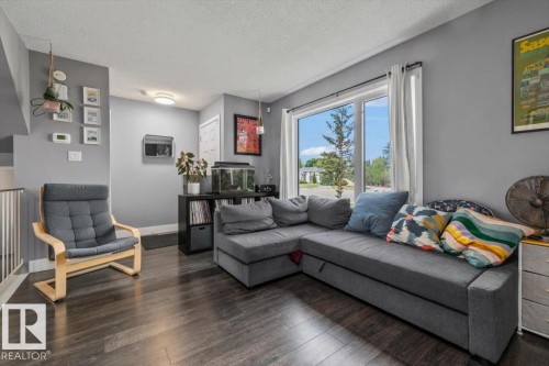 Hardwood-style flooring throughout, an expansive window, and a built-in railing - 1040 Lakewood Rd N Nw, Edmonton, AB 