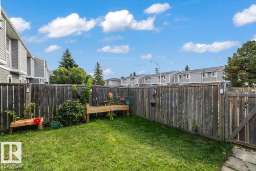 Fenced backyard with a grass lawn, featuring a wooden garden bed and planted shrubs - 1040 Lakewood Rd N Nw, Edmonton, AB 