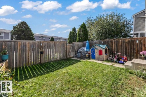 Fenced backyard with a grassy lawn, concrete pavers, and a built-in planter box - 1040 Lakewood Rd N Nw, Edmonton, AB 