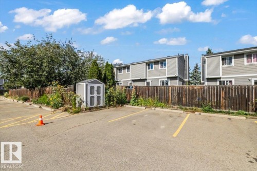 Paved parking area featuring striped parking stalls, a wood fence, and a storage shed - 1040 Lakewood Rd N Nw, Edmonton, AB 