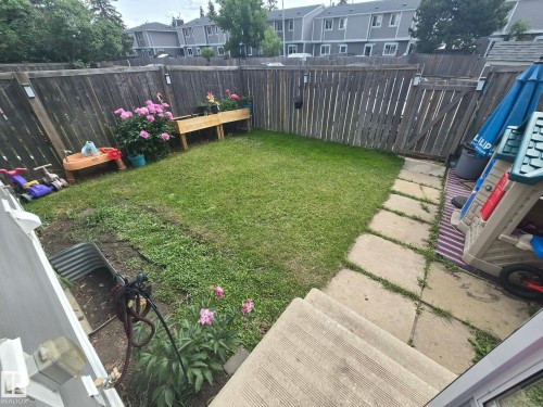Expansive private yard featuring a wood fence, concrete paver pathway, and garden beds - 1040 Lakewood Rd N Nw, Edmonton, AB 