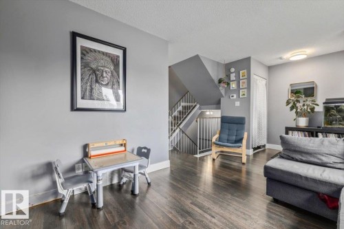 Wood-finish flooring throughout, gray wall paint, and a built-in staircase with white railings - 1040 Lakewood Rd N Nw, Edmonton, AB 