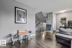 Wood-finish flooring throughout, gray wall paint, and a built-in staircase with white railings - 
