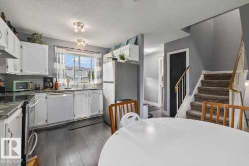 Kitchen featuring white cabinetry, gray countertops, and stainless steel appliances - 1040 Lakewood Rd N Nw, Edmonton, AB 