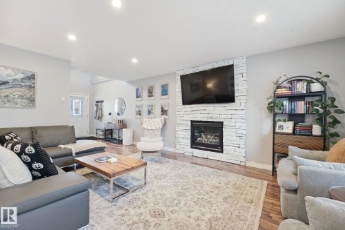 Living area with wood-finish flooring, recessed lighting, and a white stacked stone fireplace - 324 Ascott Crescent, Sherwood Park, AB 