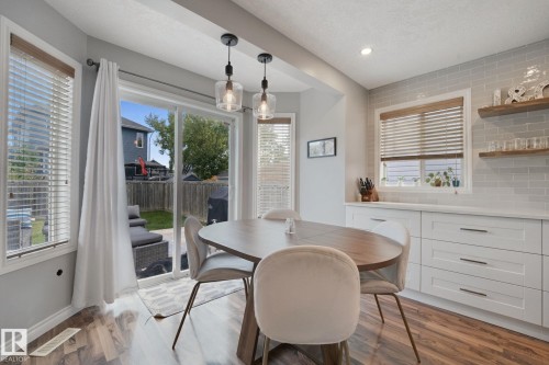 Wood-finish flooring throughout, white shaker-style cabinetry with dark pulls, light gray subway tile backsplash, recessed lighting, and dual pendant lights - 324 Ascott Crescent, Sherwood Park, AB 