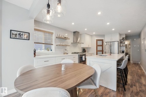 Kitchen featuring white cabinetry, stainless steel appliances, a white island with seating, a tile backsplash, and recessed lighting - 324 Ascott Crescent, Sherwood Park, AB 