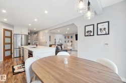 Kitchen with stainless steel appliances, white cabinetry, a center island with sink, wood-finish flooring, and recessed lighting - 
