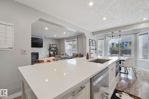 Kitchen island with a built-in stainless steel sink, integrated dishwasher, and white countertop - 324 Ascott Crescent, Sherwood Park, AB 