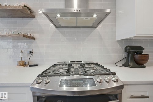 Stainless steel range with a built-in oven, stainless steel range hood, white subway tile backsplash, white countertops, and white cabinetry - 324 Ascott Crescent, Sherwood Park, AB 