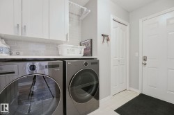 Laundry area featuring white cabinetry, a light-toned countertop, and a tiled backsplash - 